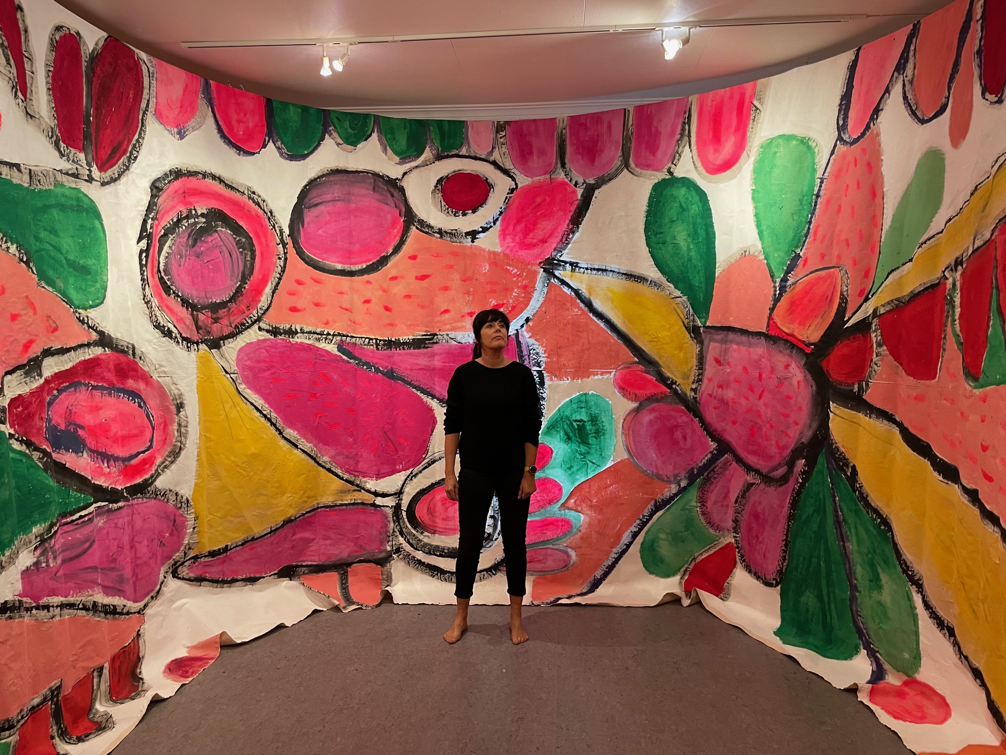 Kunstner Kristin Jensen Romberg står foran ett av sine fargerike verk